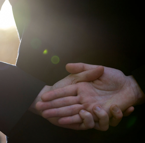 Hands held respectfully behind the back of a man in uniform.